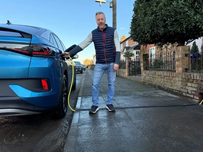 Man charging EV using cross pavement EV gully outside his house