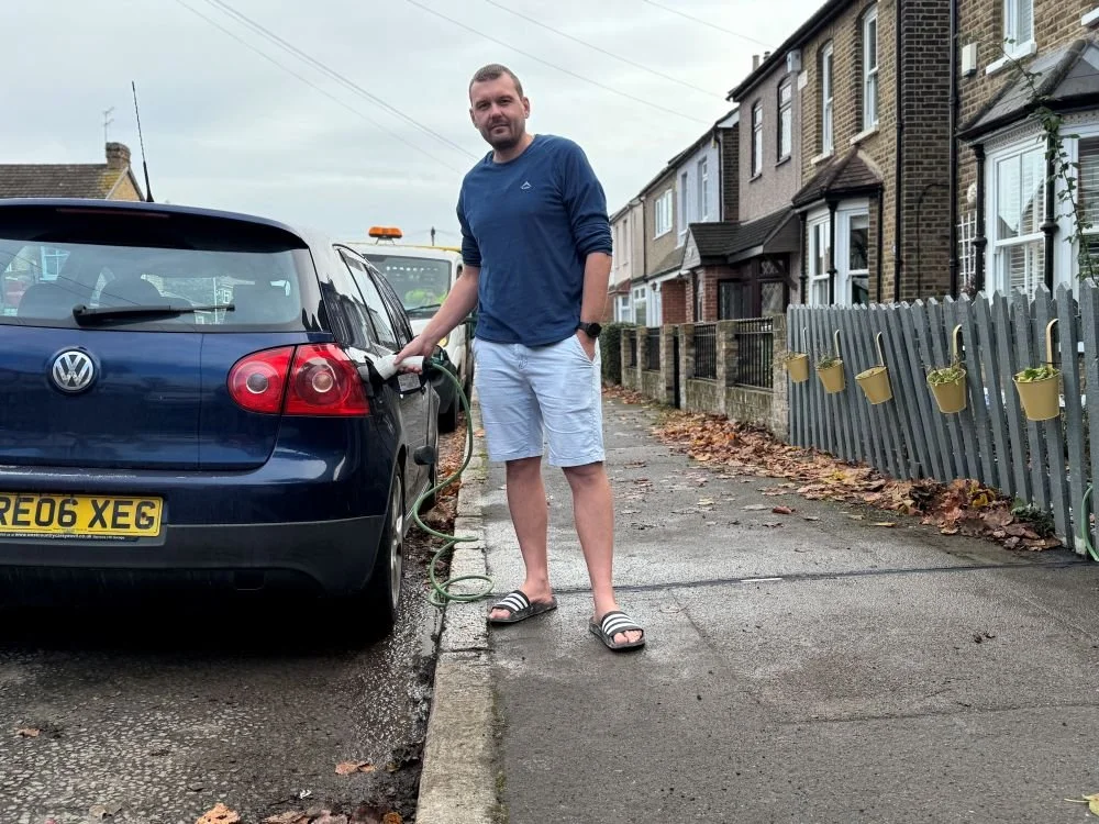 Man in short and long sleeved tshirt charging his EV at the side of the road