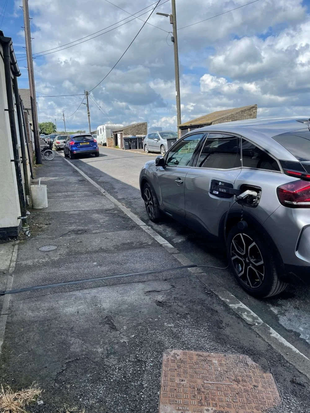 Car being charged by the side of the road via an EV cable gully
