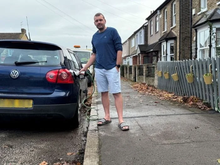 Man in short and long sleeved tshirt charging his EV at the side of the road