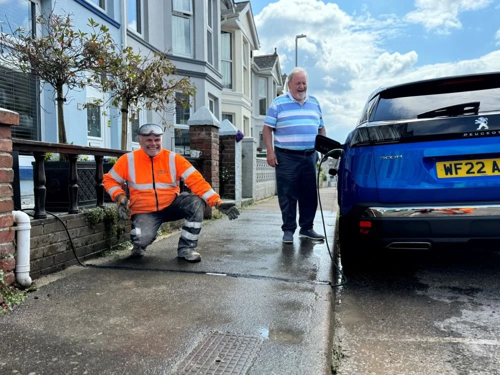 Resident and workman charging car outside home with street parking