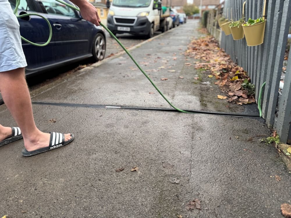 Man in flip flops extracting an EV cable from a cable gully in the pavement