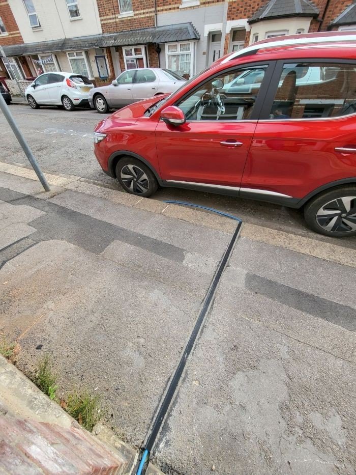 Red Electric car parked on street being charged