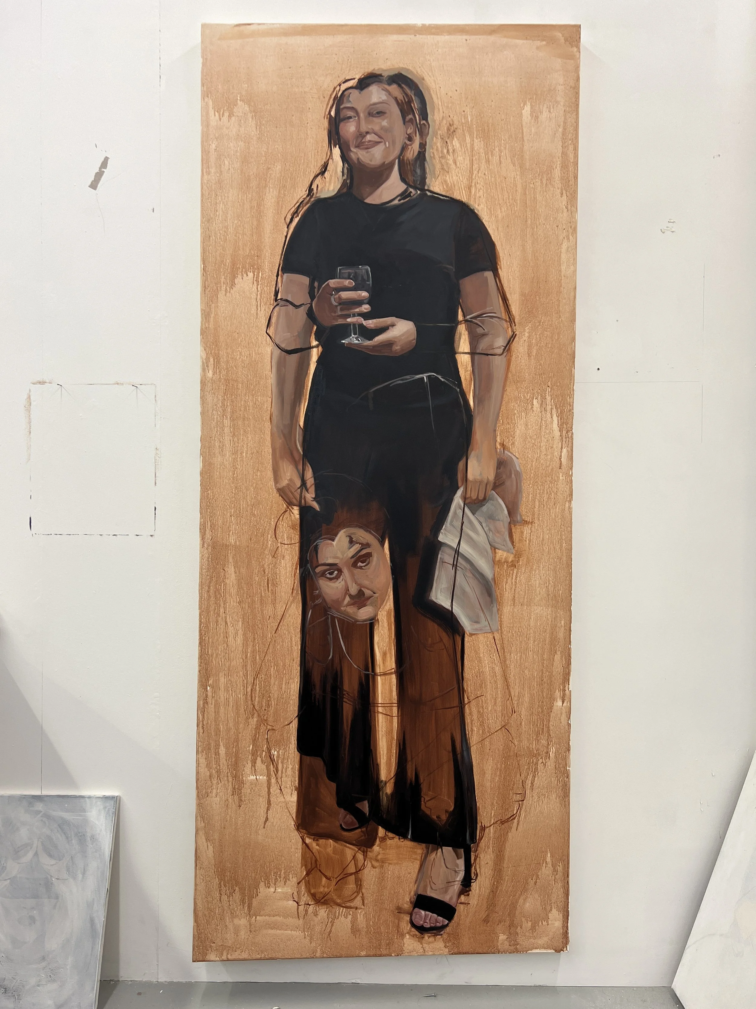 A painting of a woman standing and smiling, wearing a black shirt and pants, holding a wine glass, with another woman depicted on her pant leg, all painted on a wooden background.