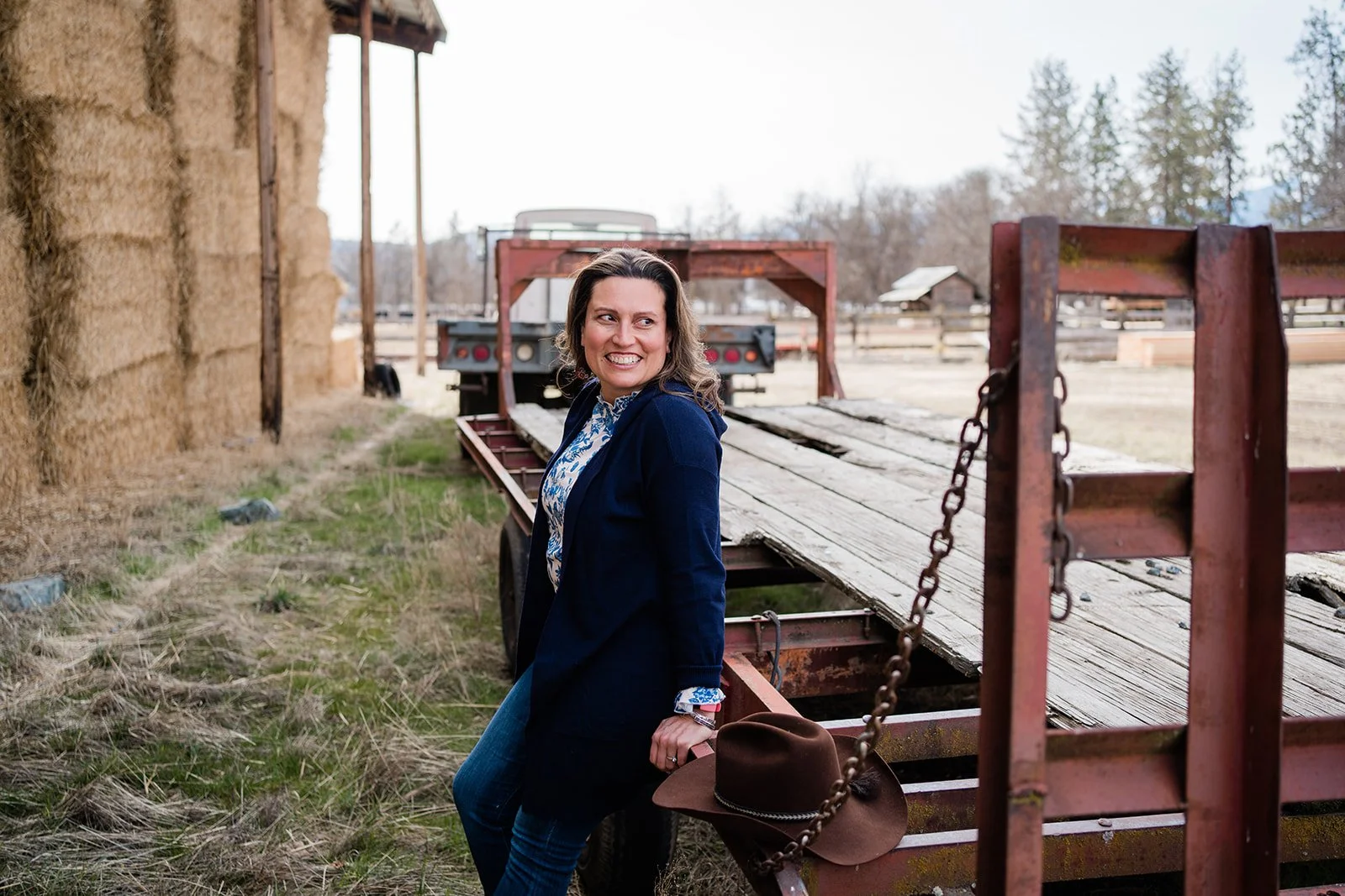 Regina leaning up agains ranch equipment near the hay barn