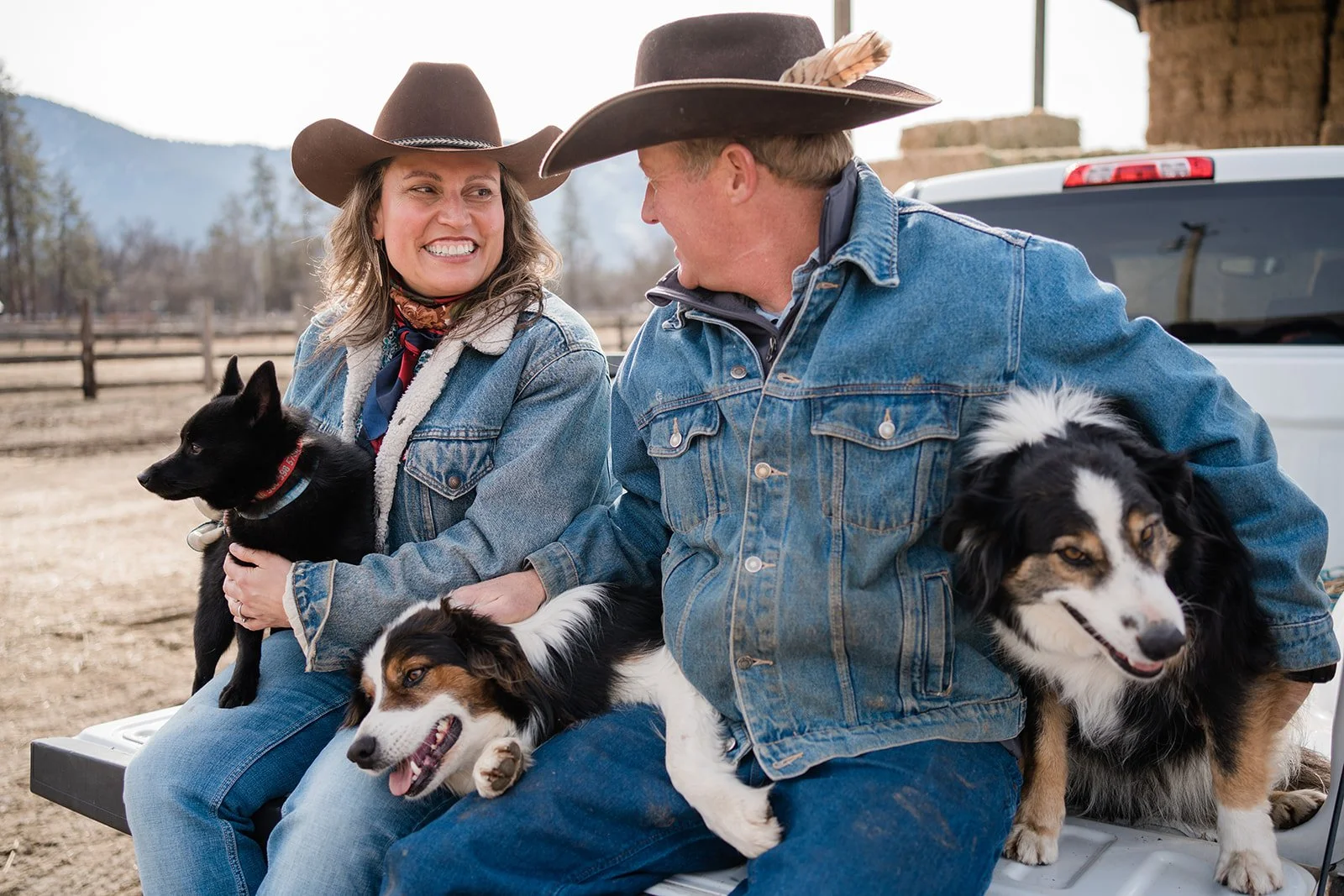 Regina and Judd Hanna sitting in the bed of their pickup with their dogs
