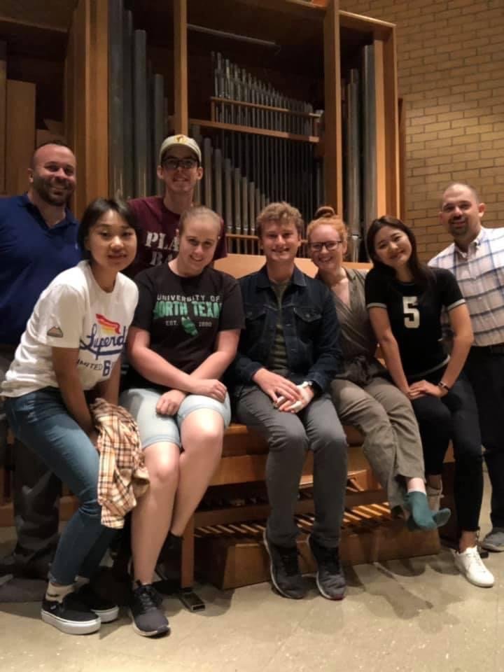Parker MacIver Hinnenkamp on the bench of the Rieger organ in UNT's infamous "Room 253," surrounded by fellow sacred music students, bookended by lecturers Dr. Michael Conrady (far left) and Dr. Josh Taylor (far right).