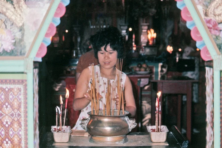 Chinese women burning incense sticks.