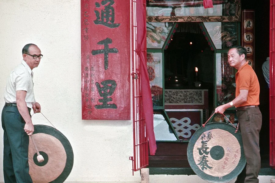 Two men preparing to play the gong.