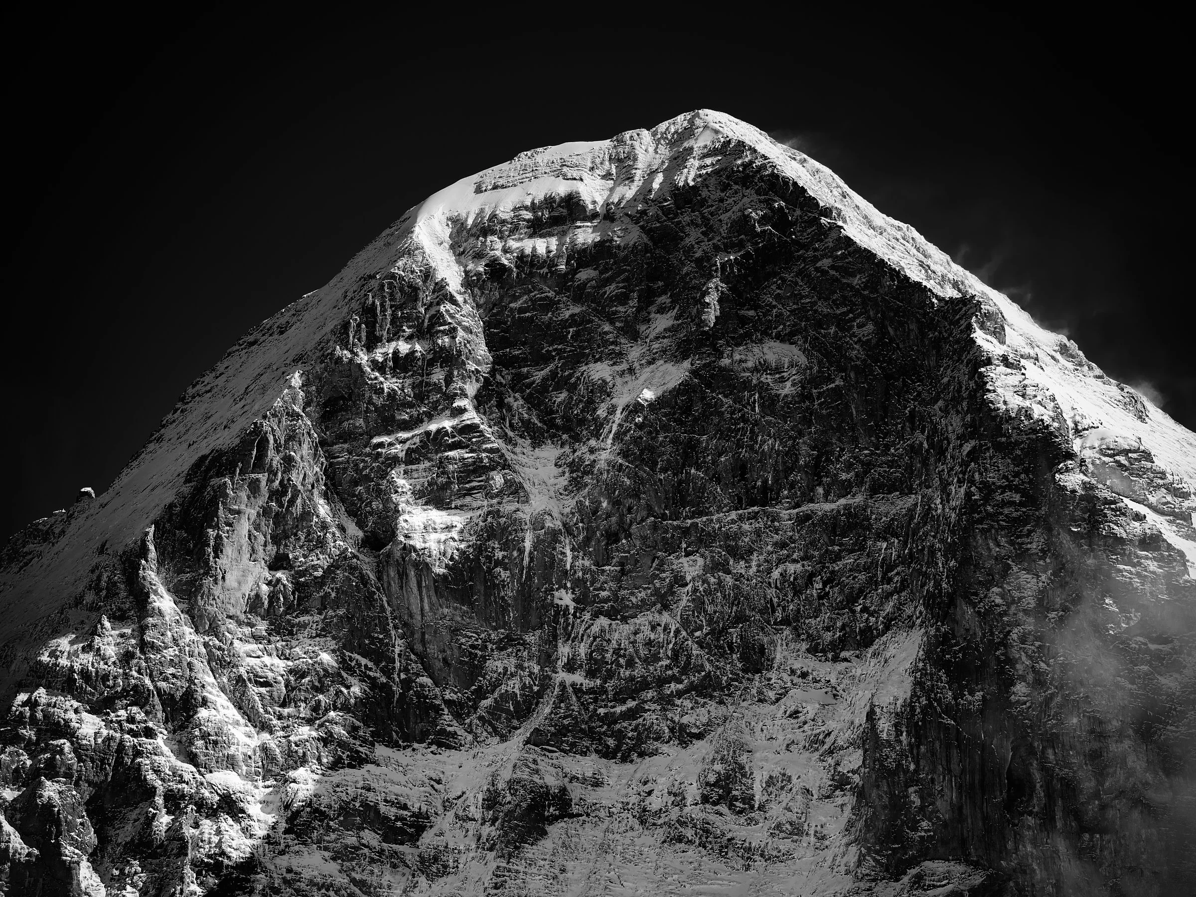 Black and white fine art of the Eiger North Face in winter. The 1,800-metre limestone wall rendered in shadow and ice, with the White Spider ice field and key features of the Mordwand visible. Fine art by Jürg Kaufmann.