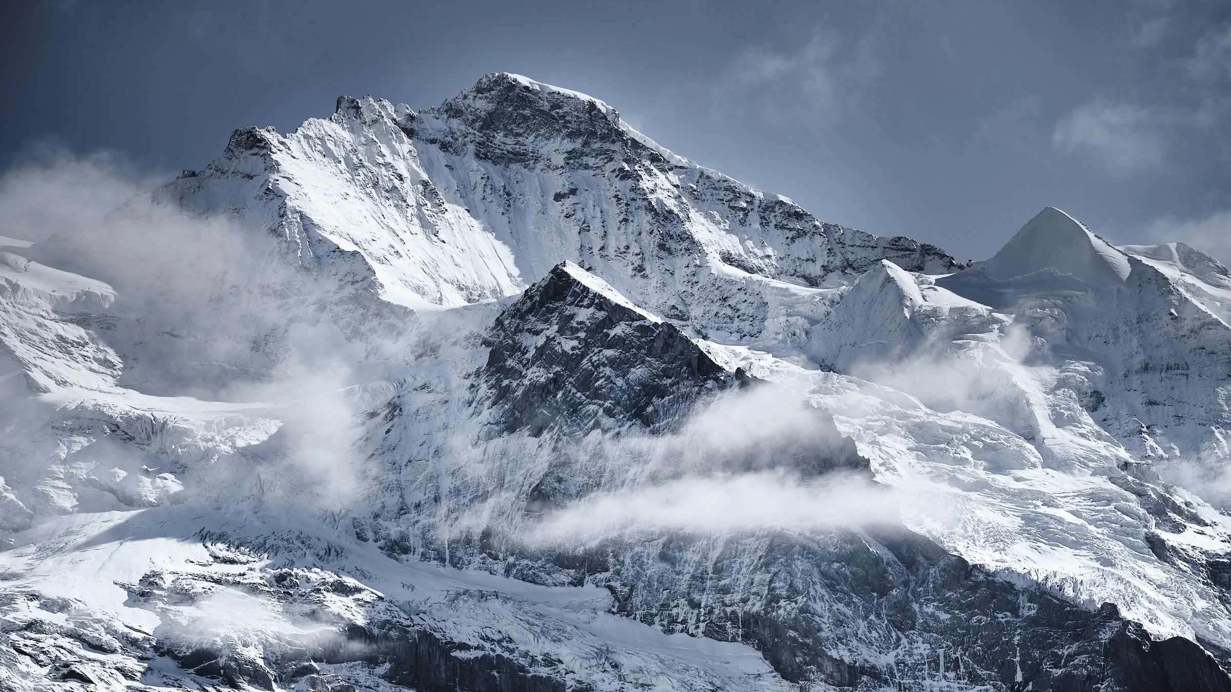 The Jungfrau north face in early September snow, with glaciers descending the north wall partly veiled by drifting clouds, seen from the Bernese Oberland. Fine art photograph by Jürg Kaufmann.