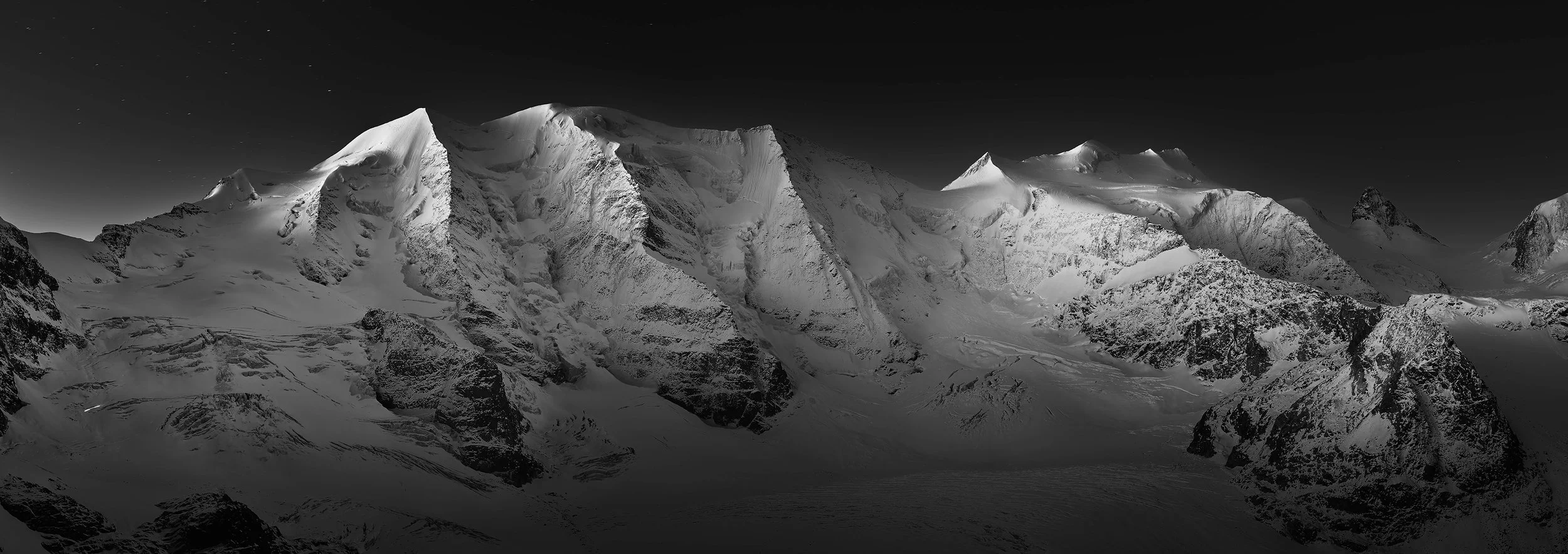 Black and white panorama of Piz Palü, Bellavista and Crast' Agüzza in moonlight before dawn, autumn, from the Diavolezza. Fine art photography by Jürg Kaufmann, Bernina Range, Engadin, Switzerland.