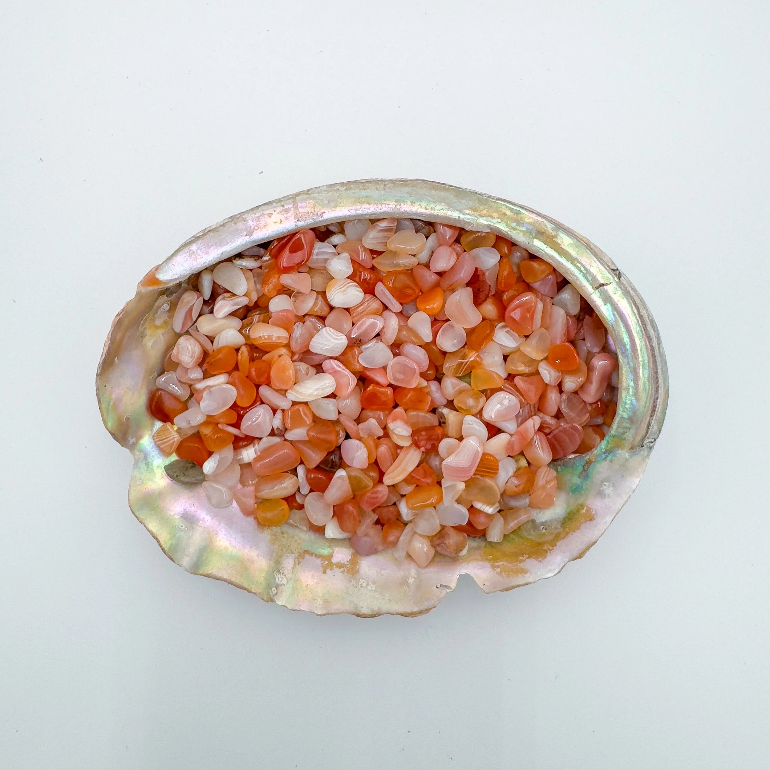 Bulk banded carnelian crystal chips – polished tumbled gray gemstone pieces with flashes of blue and green, ideal for crafts, décor, jewelry, and healing work.