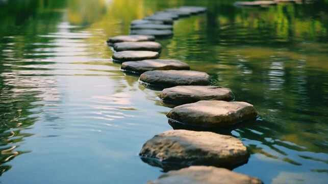 A series of stepping stones across a calm body of water.