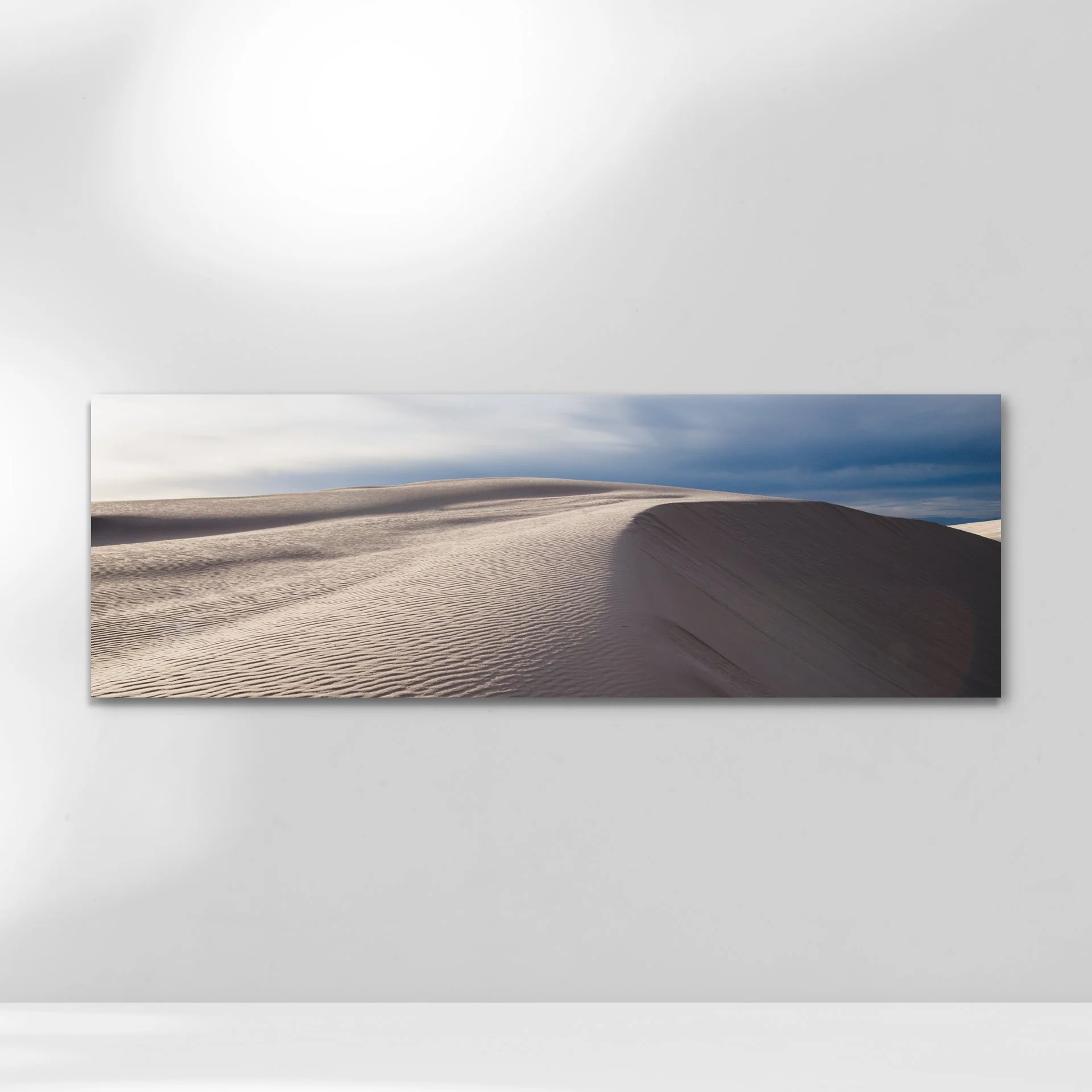 Smooth, wind-swept sand dunes under a soft blue sky with subtle clouds.