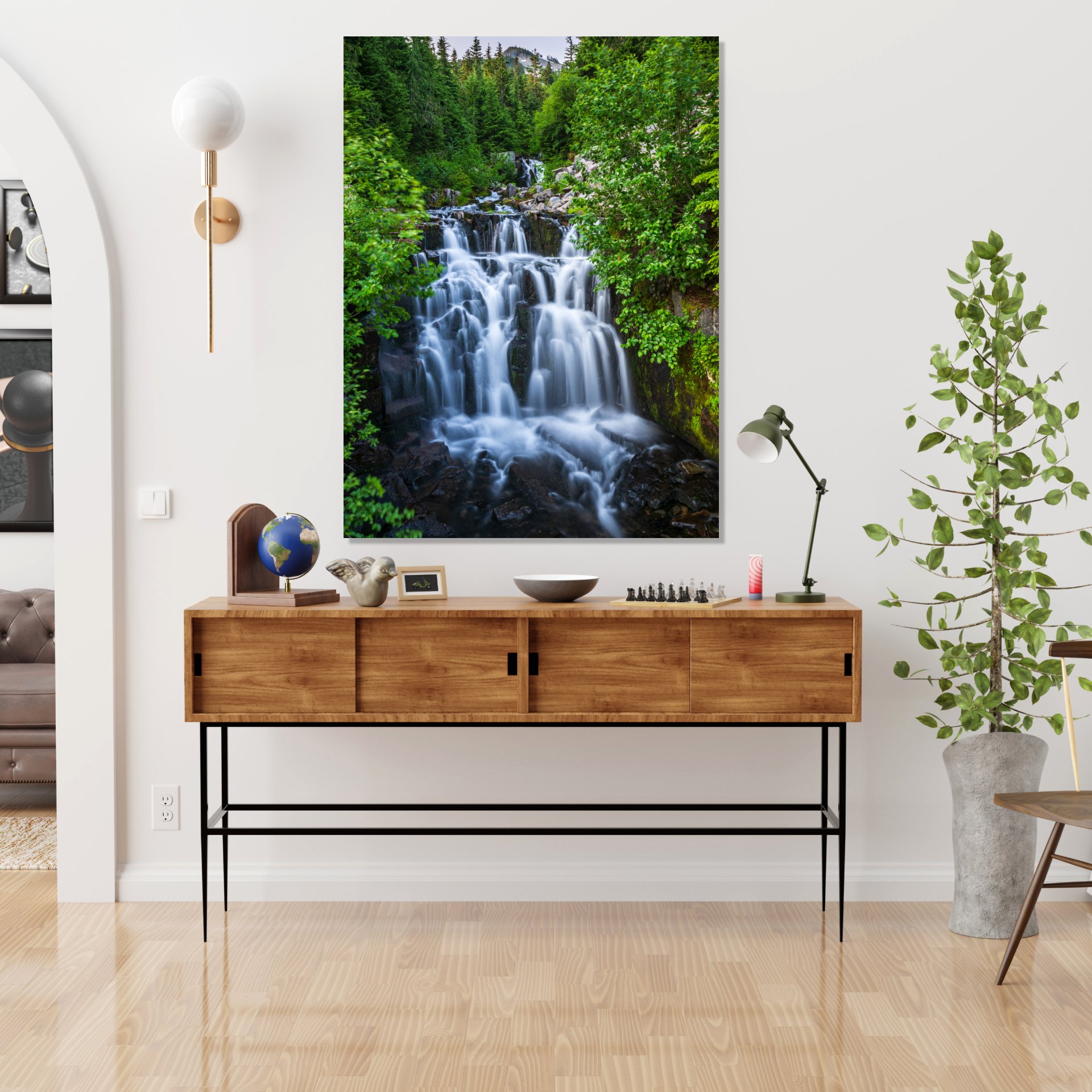 Waterfall cascading through a forest, with greenery and a distant peak.