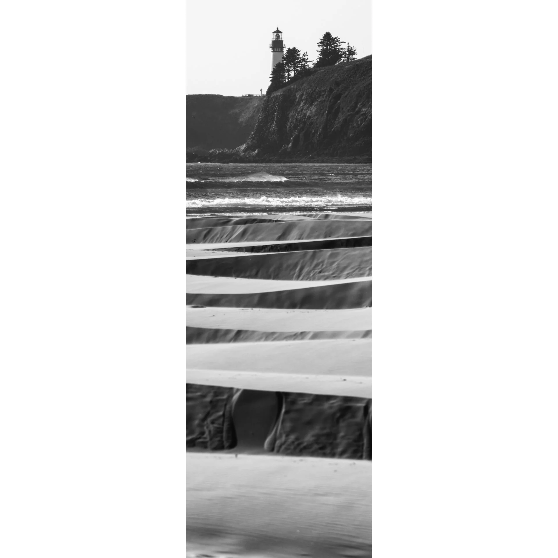 Lighthouse atop a cliff with windblown sand ripples in the foreground.