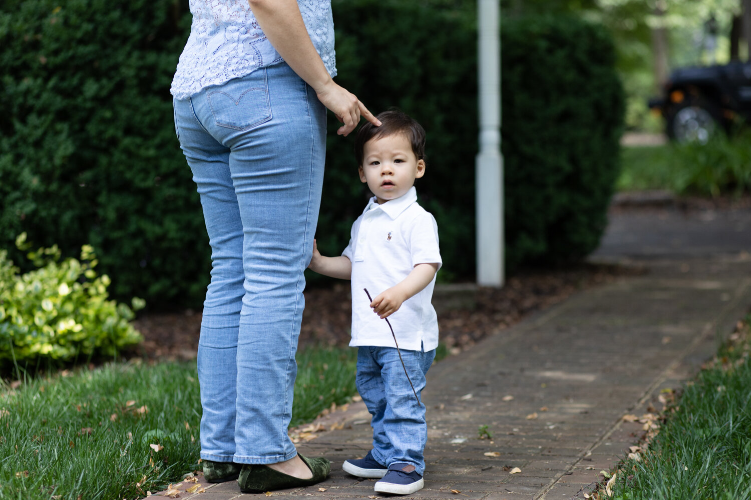 Shy toddler standing with Mom during backyard family photos
