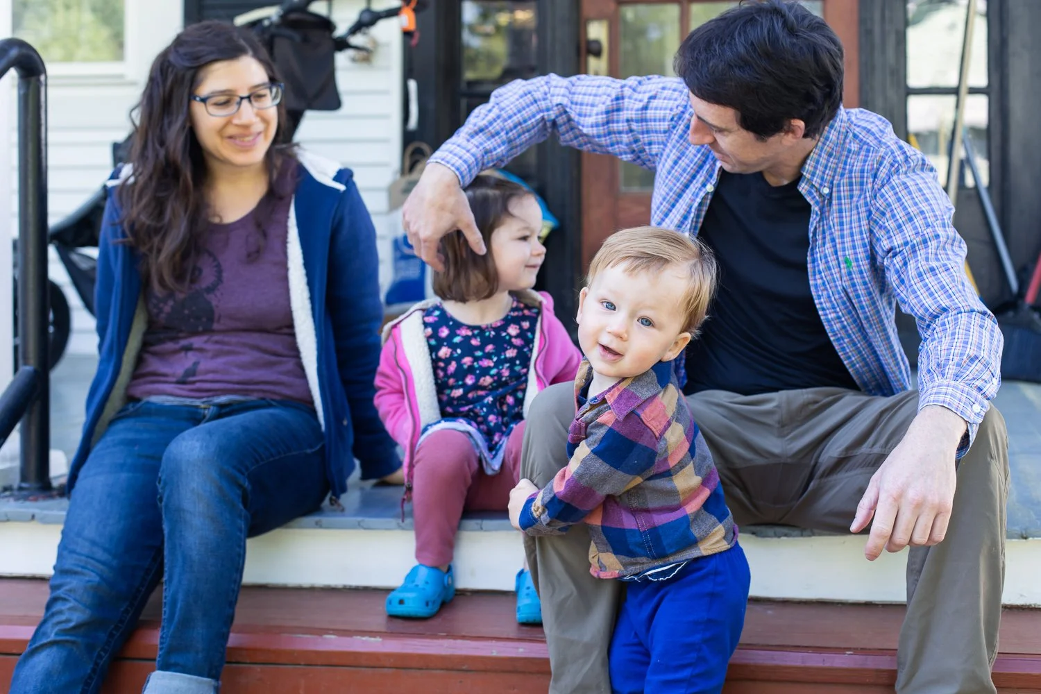 A family sits together on their front porch in Richmond, Virginia, during a family photo session.