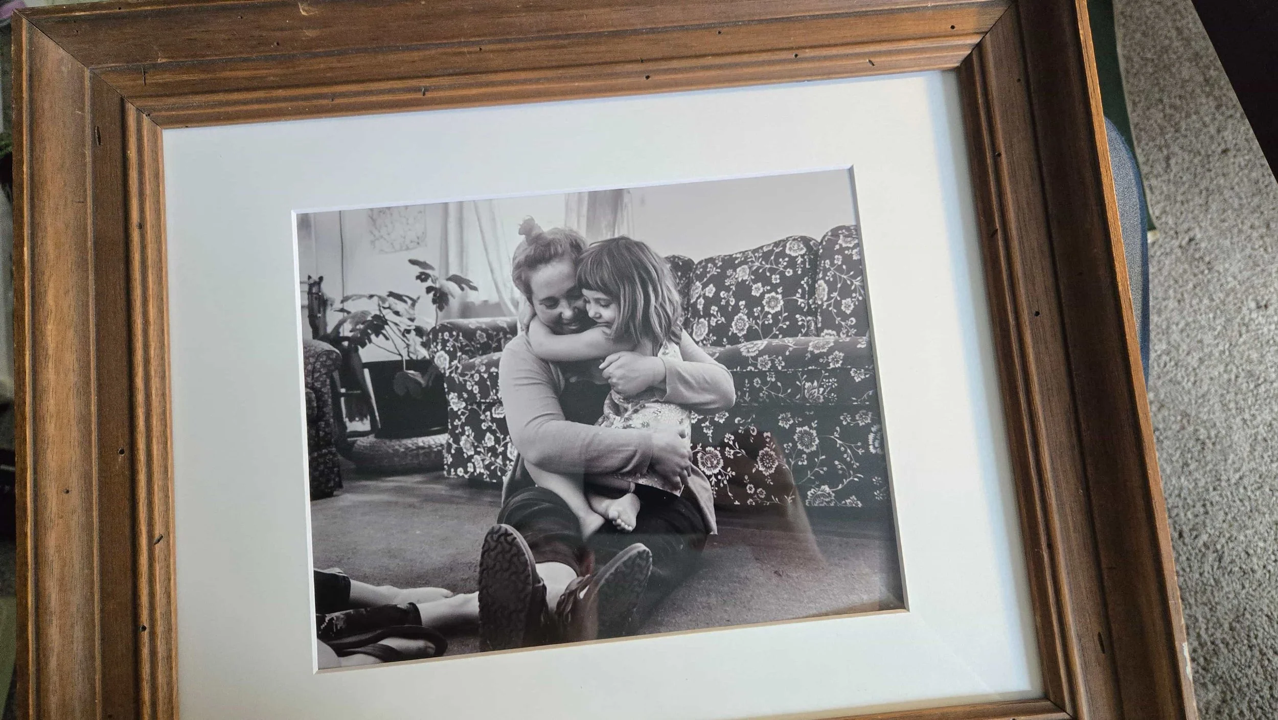 A vintage wooden picture frame being reused with a new mat and client photo.