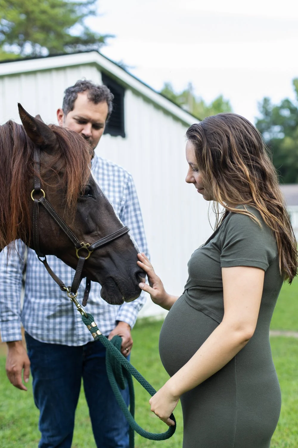 A pregnant woman stands with her horse and her husband in her yard in Varina, Virginia.