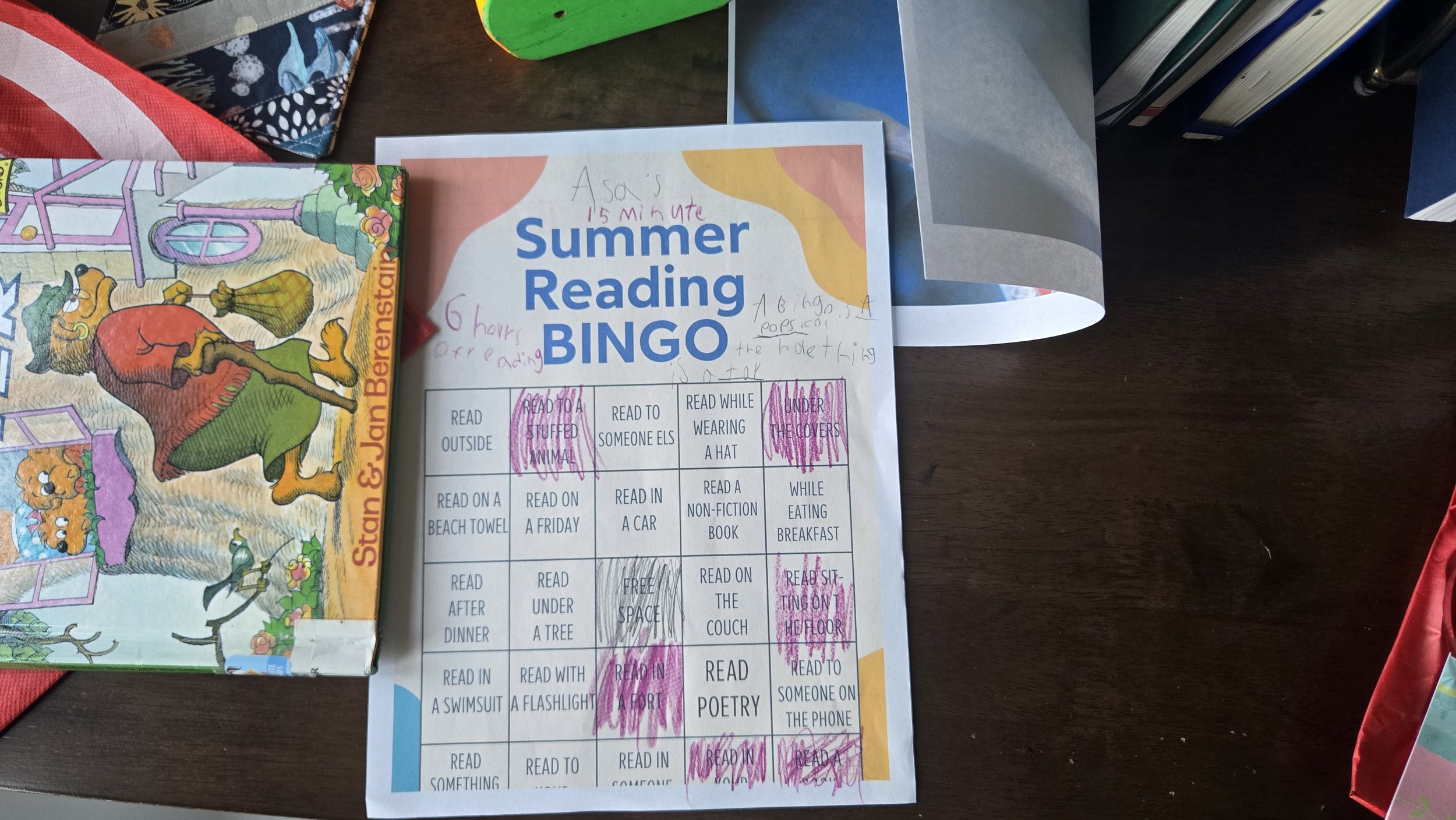An overhead image of a Summer Reading Bingo sheet that a small child has written and scribbled on