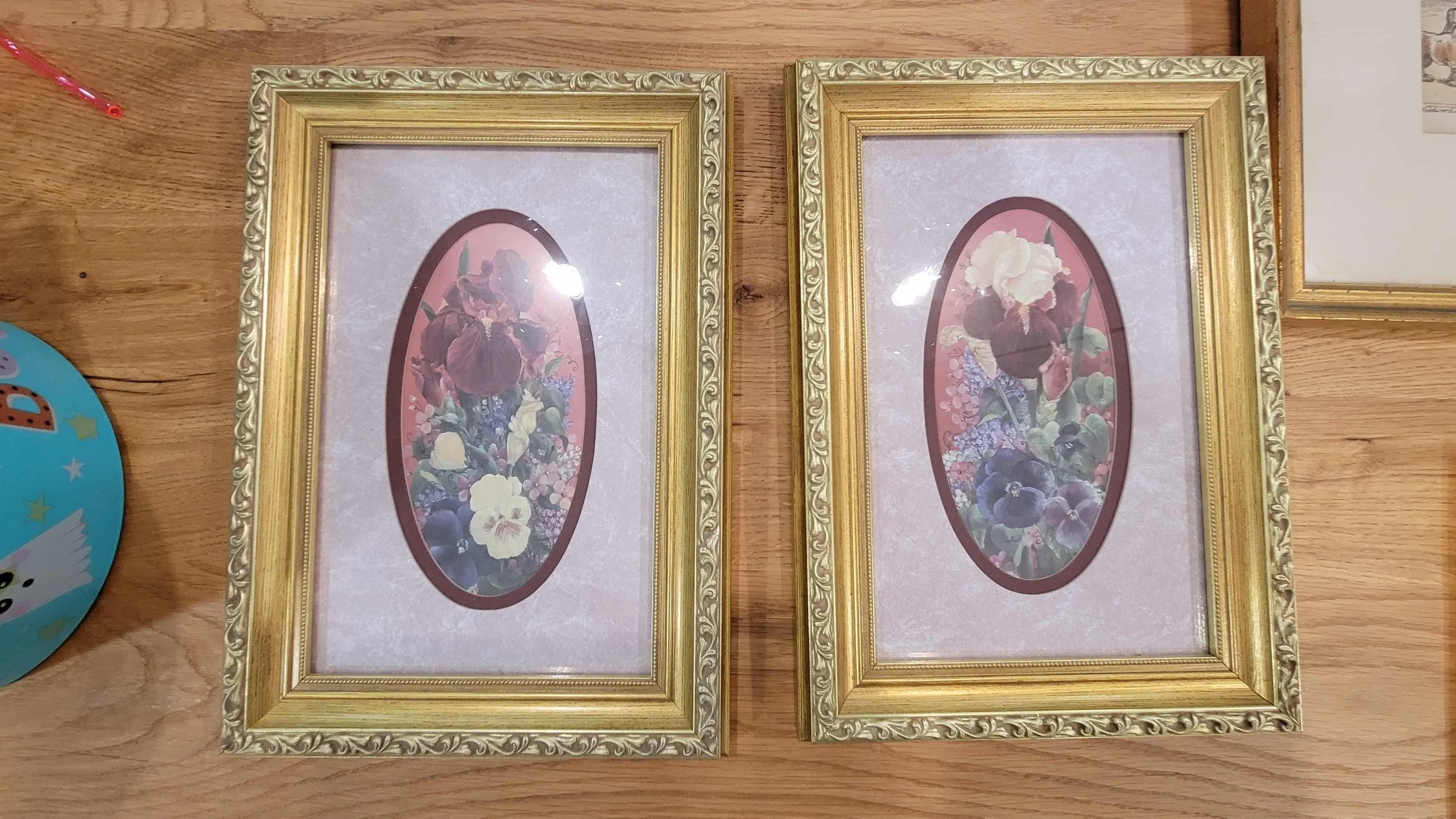 A pair of gold frames with old floral prints in them, before I repurposed them for photos.