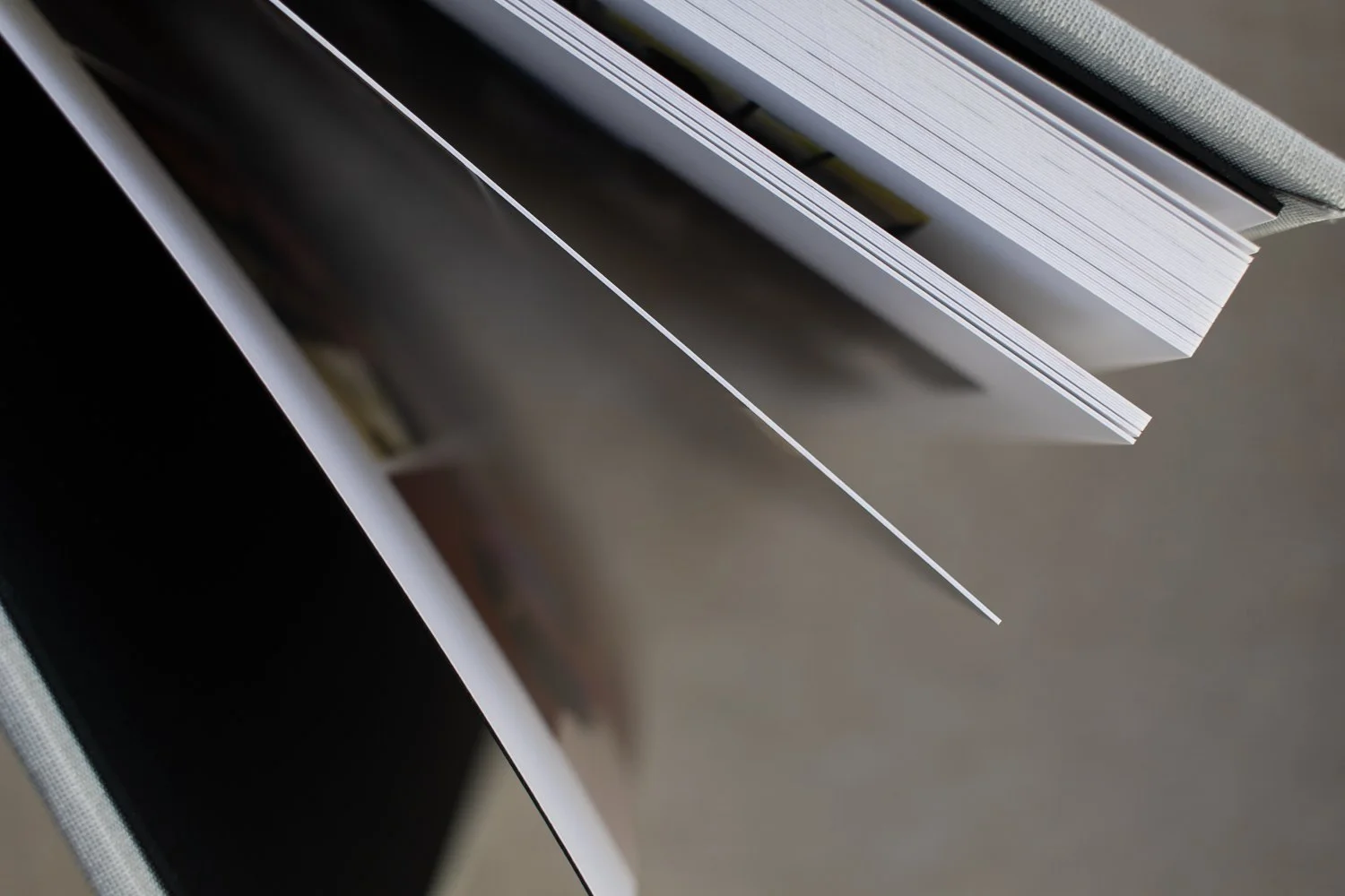 A bound, professionally printed photo book stands on its end, the pages fanned out to show their sturdiness.