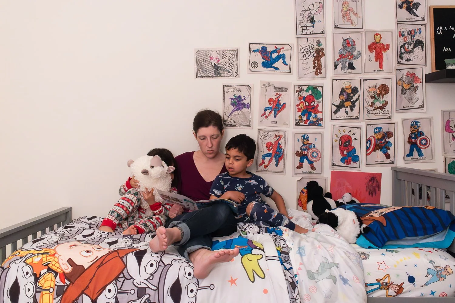 Allison Patel reading a book with her kids at bedtime. Her daughter hugs a stuffed sheep in front of her own face, and her son is tucked into her arm.