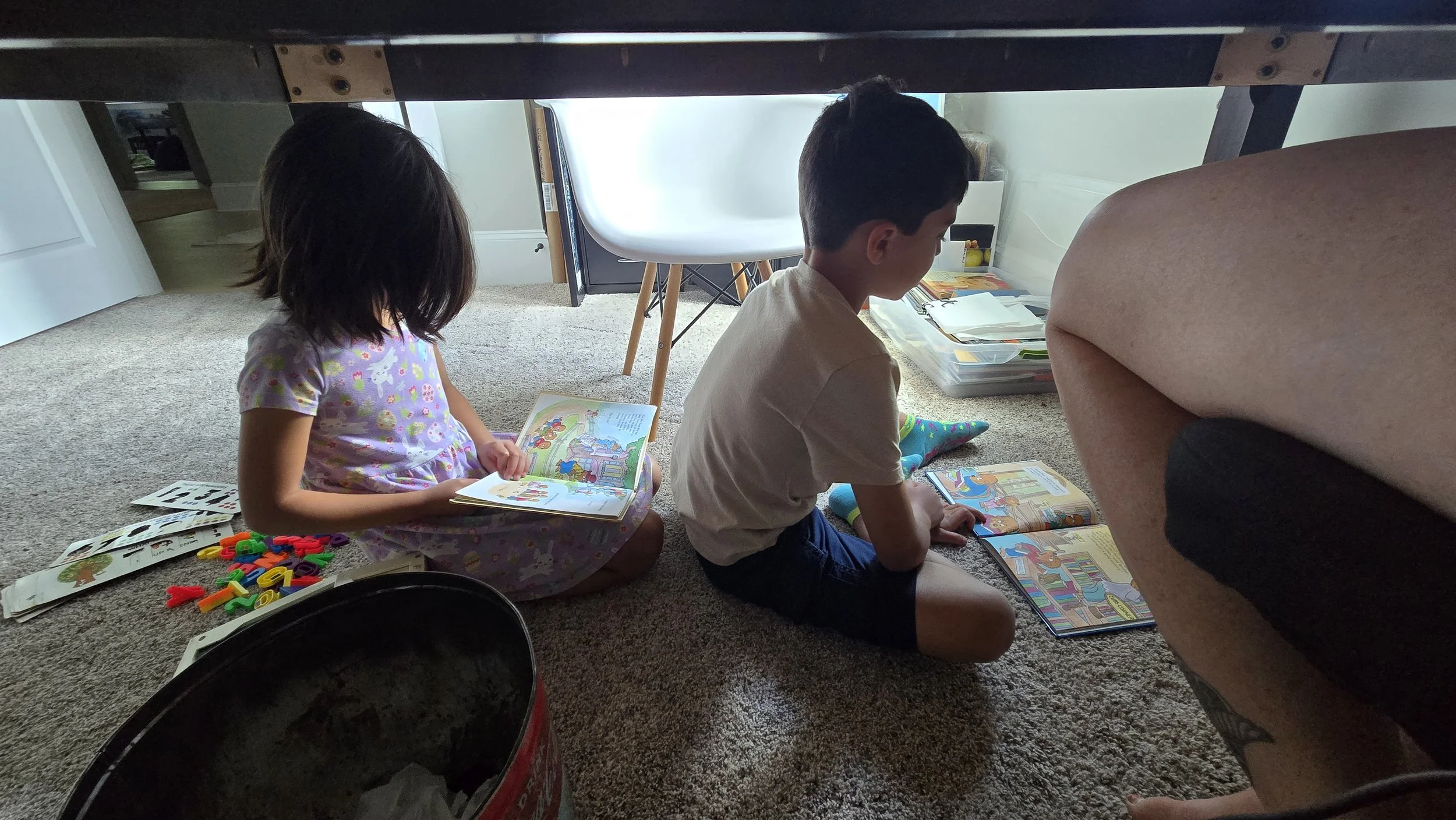 Two children reading books under the desk where the author is working.