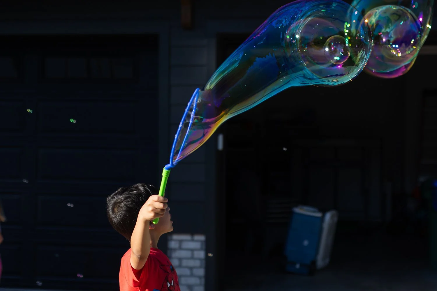 A little boy creates a huge bubble with a bubble wand in his driveway in Midlothian, Virginia.