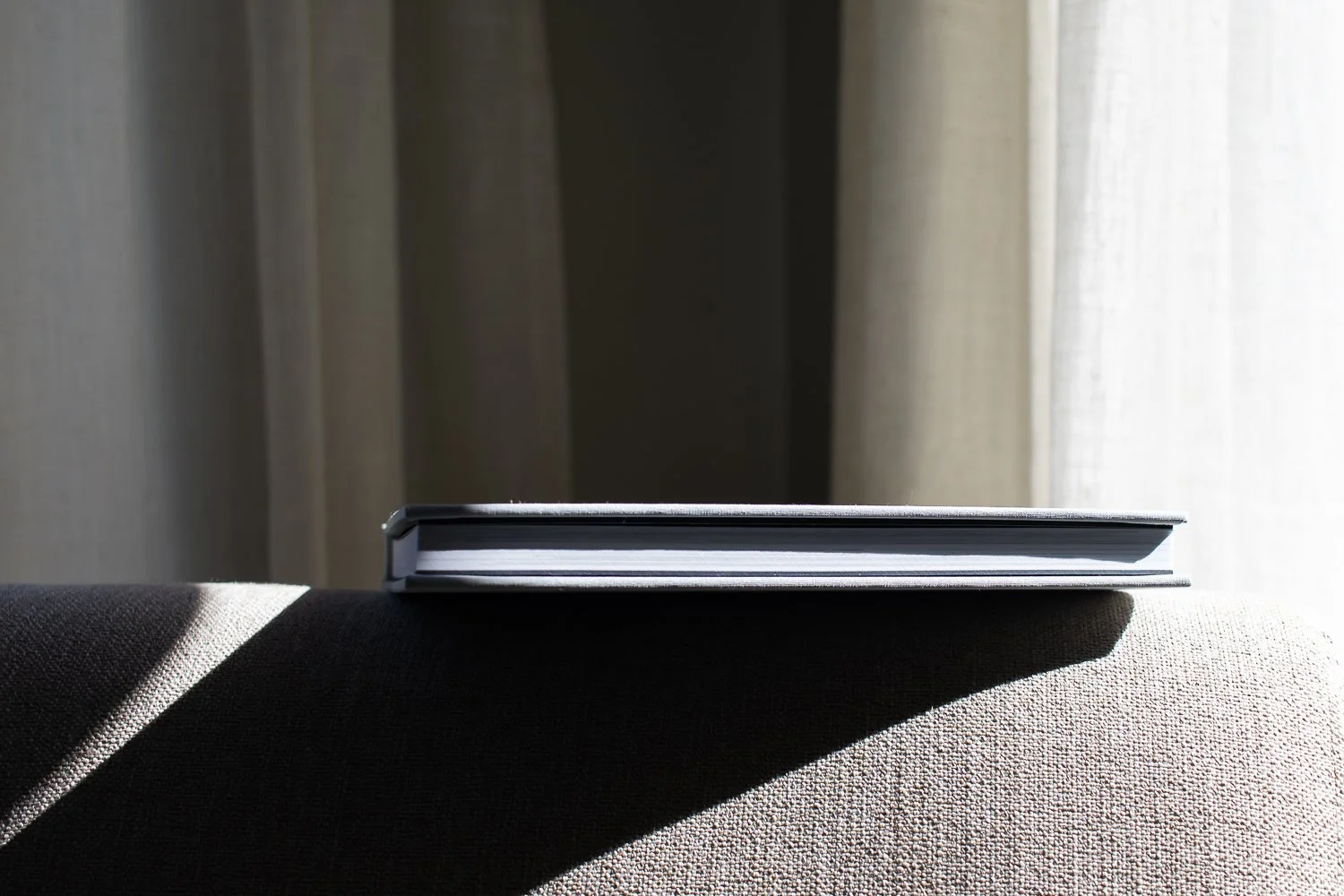 A fabric-covered photo book sitting in sunlight.