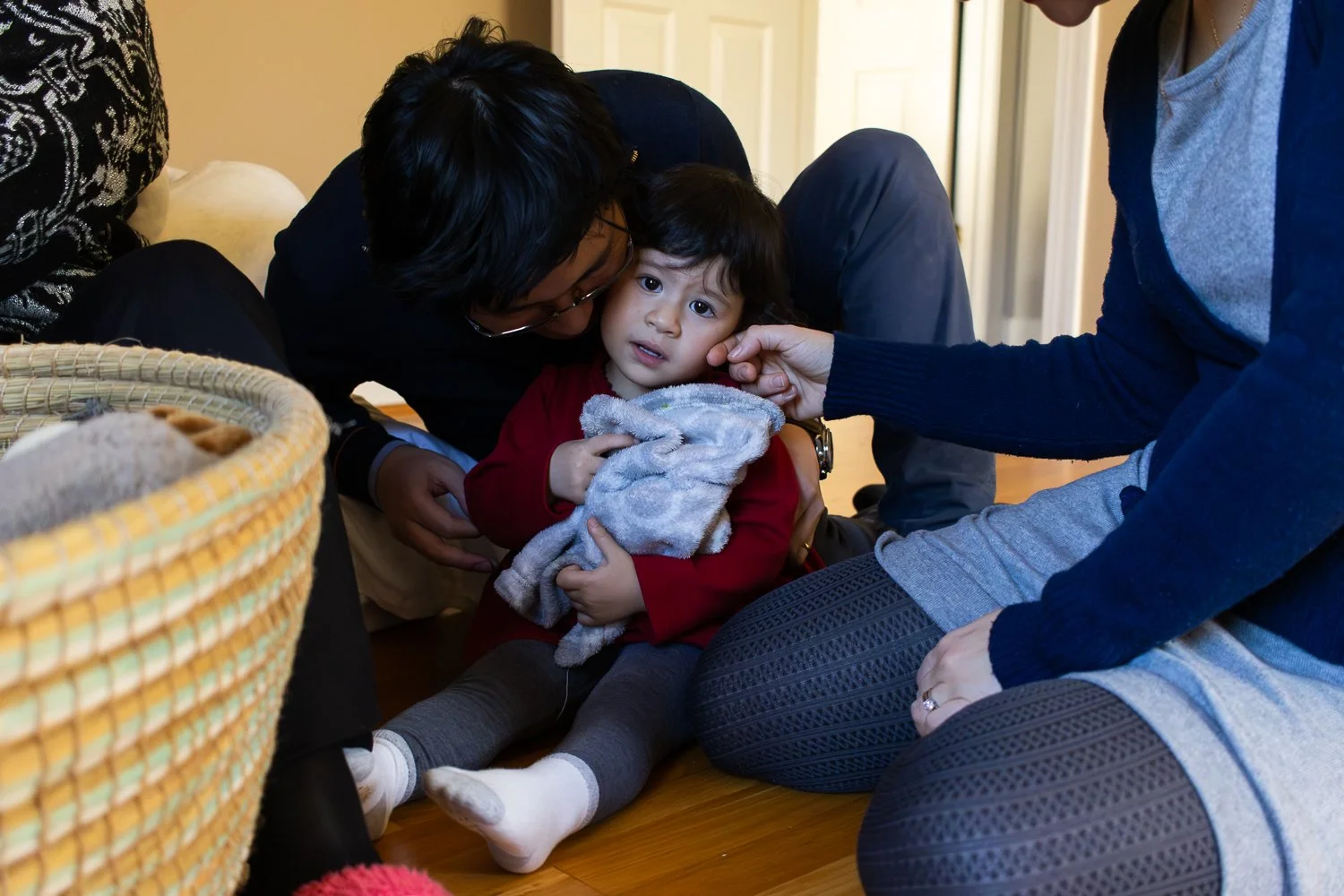 Parents comfort their anxious daughter during a lifestyle family photo session at home.