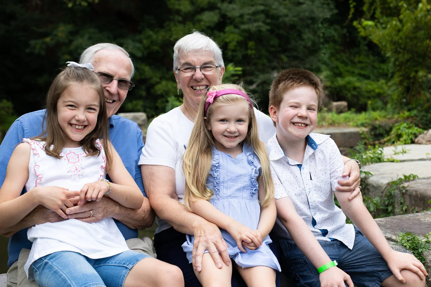 Grandparents sit with grandkids on a rock in Pump House Park in Richmond, VA.