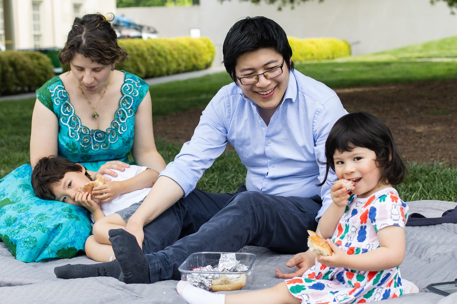 A family of four sits on a blanket on the ground at the VMFA and eats a picnic lunch.