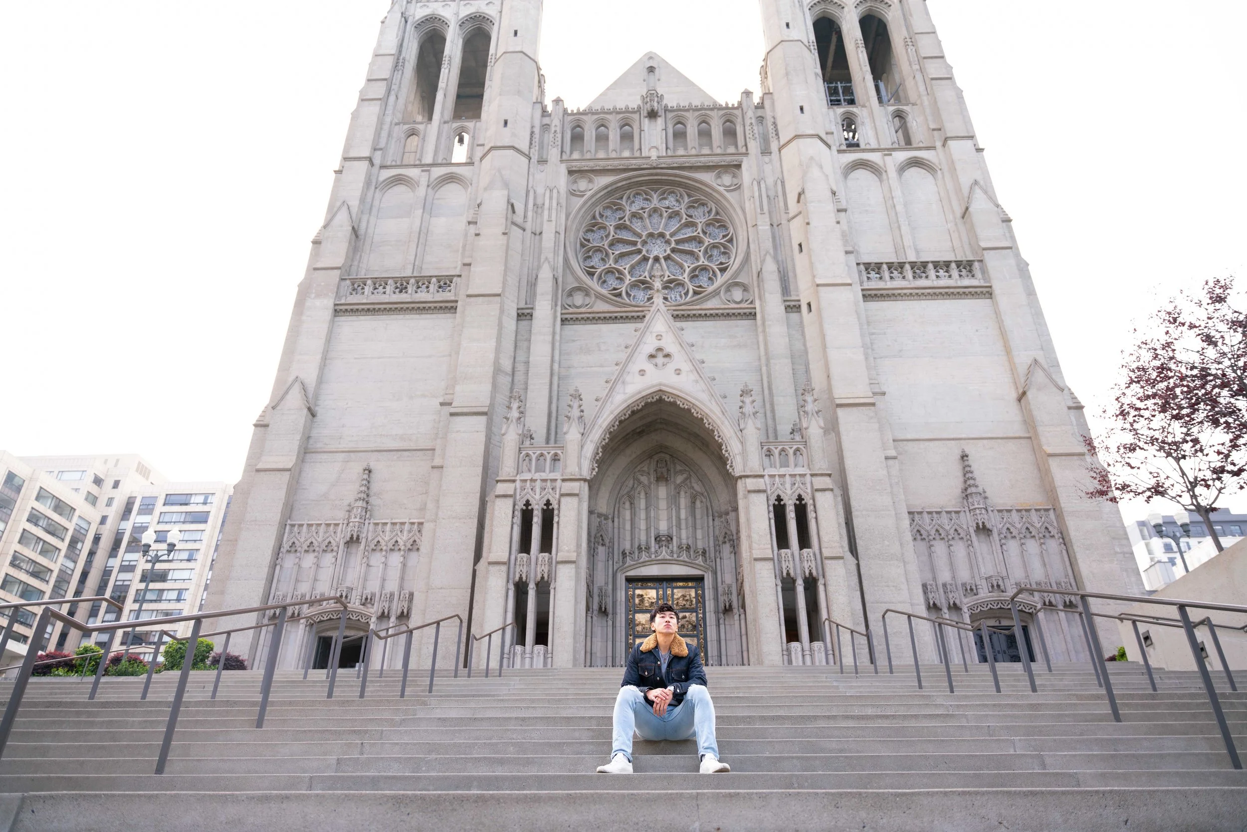 Person sitting on the steps in front of a large Gothic-style cathedral