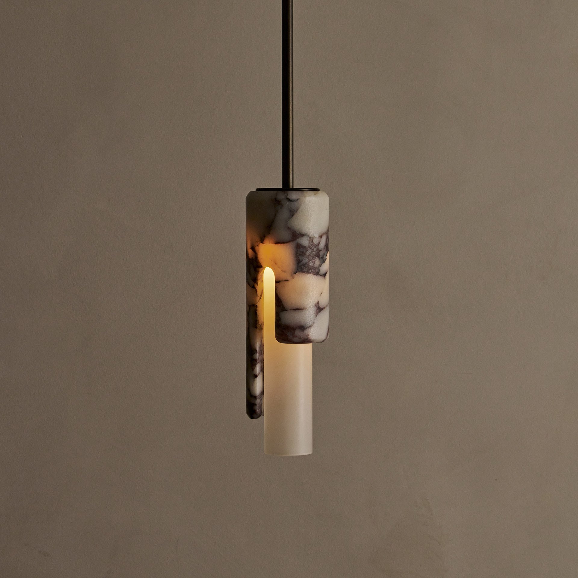 The Dover ceiling pendant features hidden fastening, seamlessly blending stone and glass components. Its cylindrical shade reveals an asymmetric profile from the side.