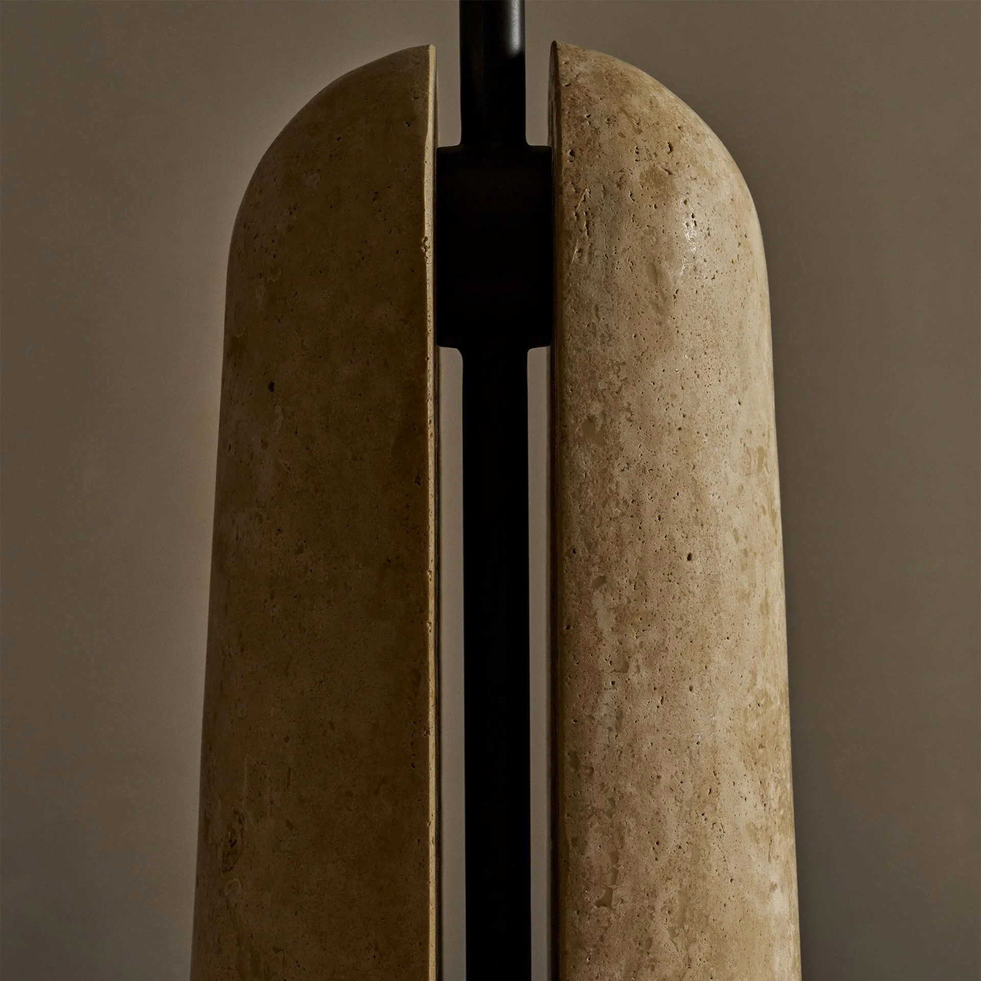 The Malt table lamp embodies unique design with its solid brass support and shade resting within a stone base, creating an intriguing blend of negative space and structural elegance.