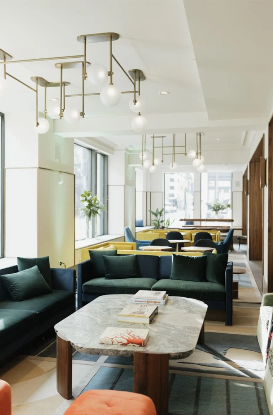 The Waymark Hotel lobby featuring a moder design, green sofa, coffee table and books, natural light.
