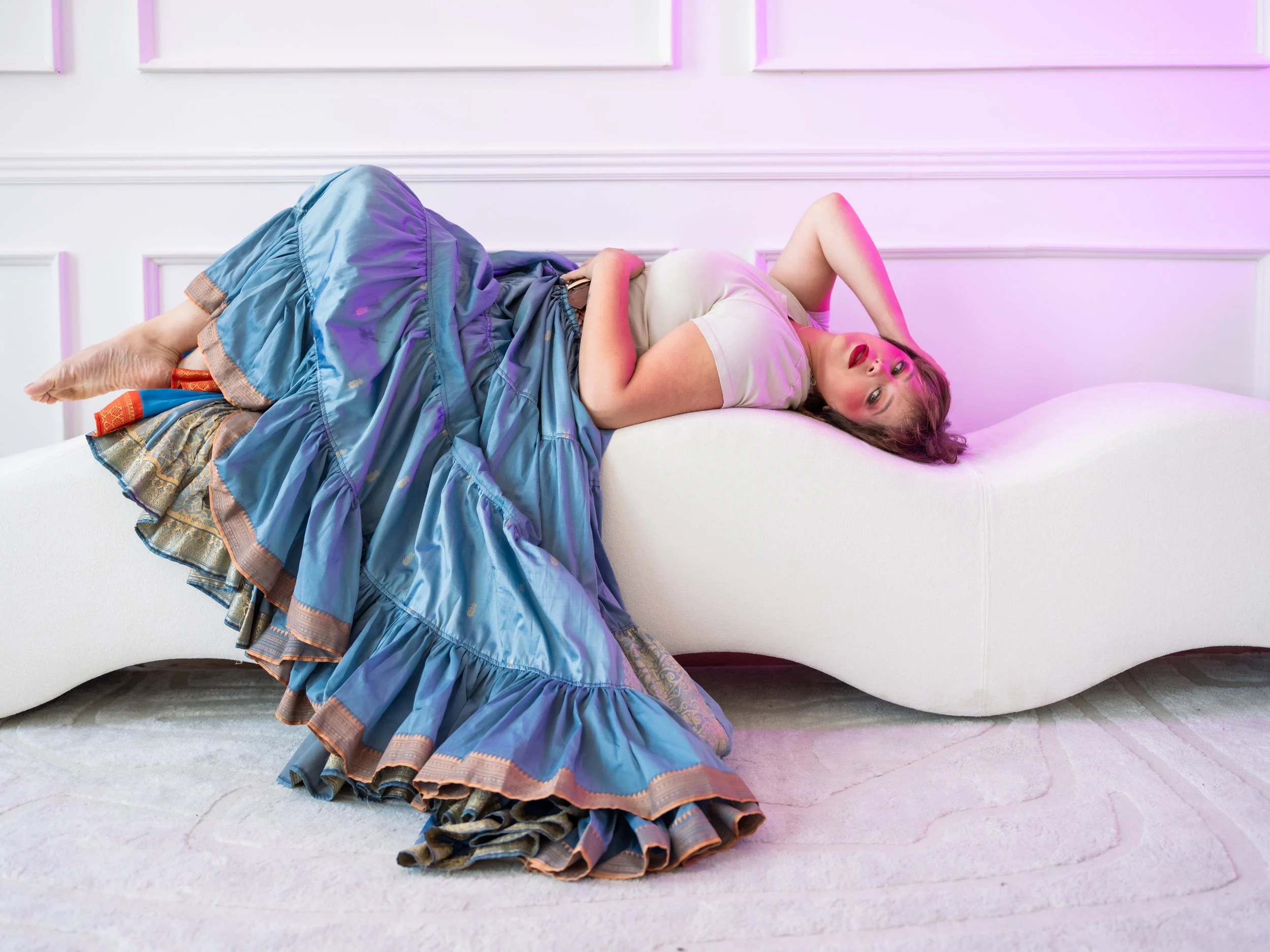 Woman in white tshirt and voluminous shirt lying on wavy couch