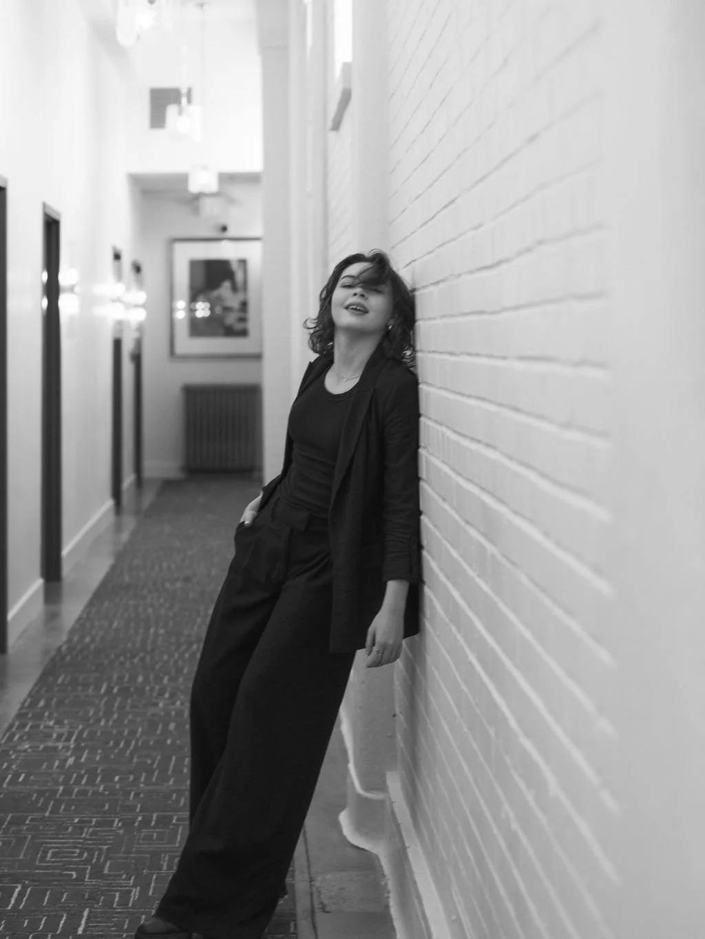 Modern black and white portrait of woman leaning against brick hotel wall, editorial style portrait photography in Louisville