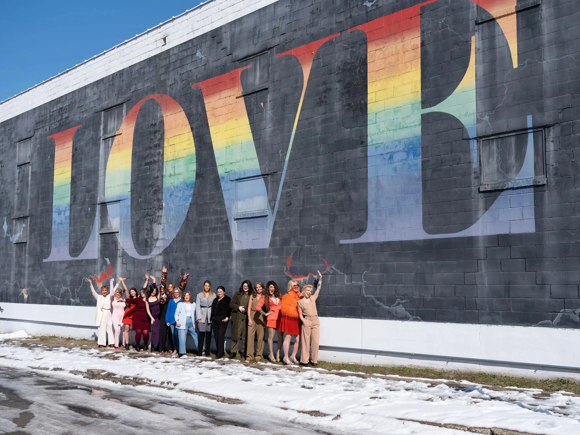 Team of Hair and Makeup artists posting by LOVE mural at Play Louisville in the winter
