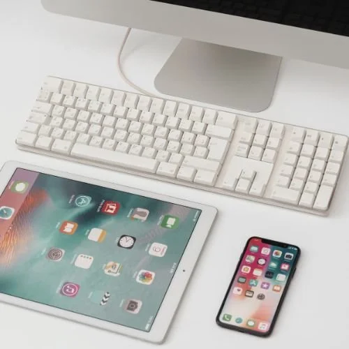 A tablet, cellphone, and computer on a desk.