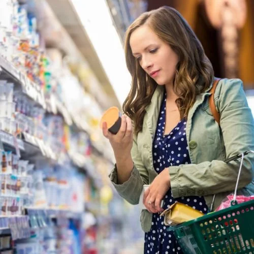 A woman at a grocery store reading a product label.