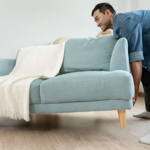 A man moving a sofa.