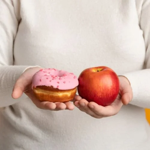 A person holding an apple in one hand and a donut in the other.
