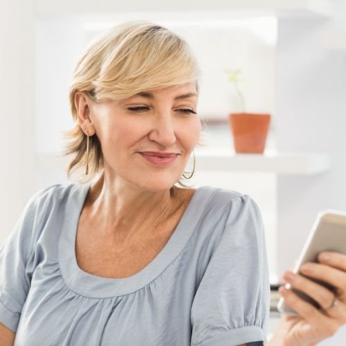 A woman looking at her smartphone. She is smiling.