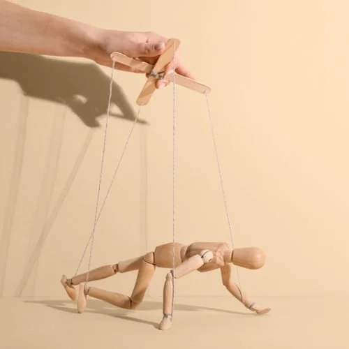A hand guiding a string puppet.