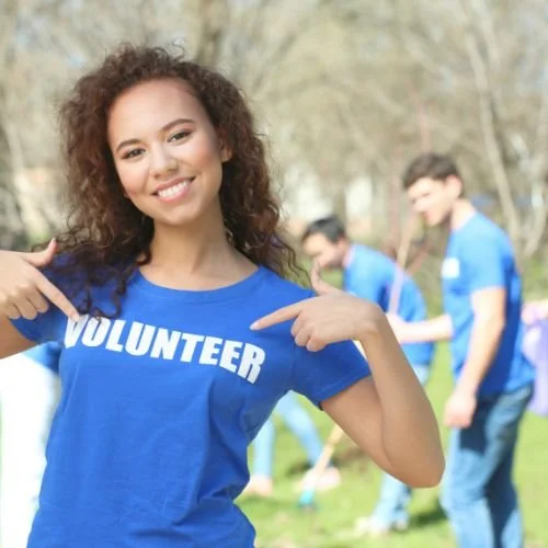 A person wearing  a t-shirt that says, 'volunteer' across the chest.