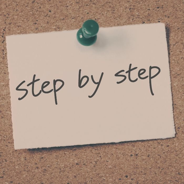 The words, "step by step" written on a sticky note.